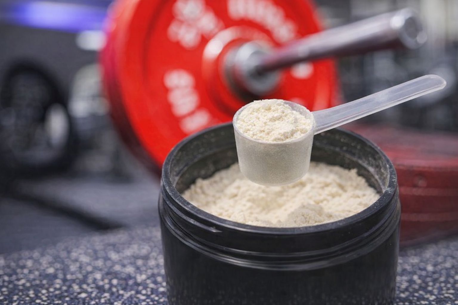 Skopa med PWO-pulver ovanför en burk med pulver i gymmet.