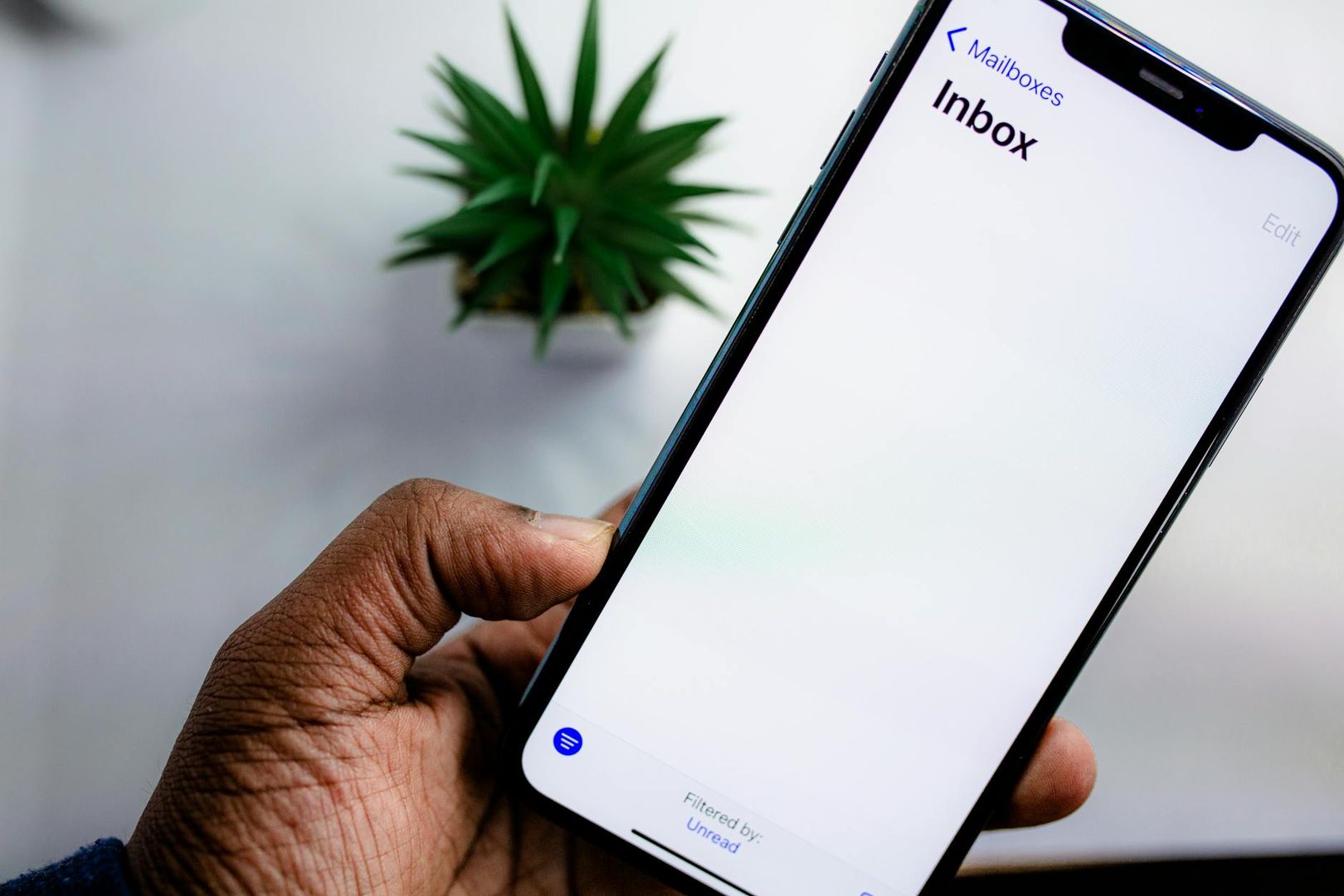 En person håller en smartphone som visar en tom inkorg filtrerad på olästa mejl.