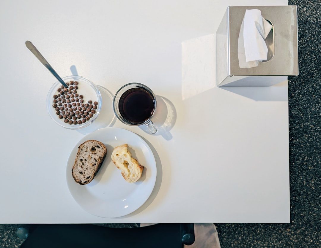 En enkel frukost med kaffe, flingor och bröd på ett vitt bord.