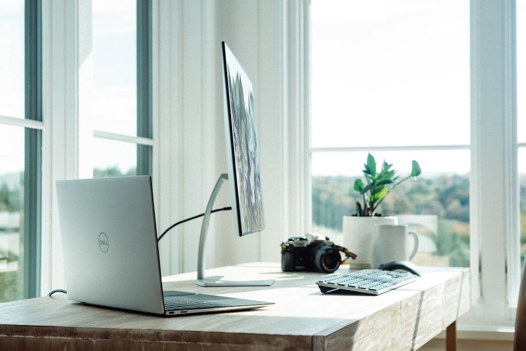 Ljust hemmakontor med laptop, skärm och dagsljus från stora fönster