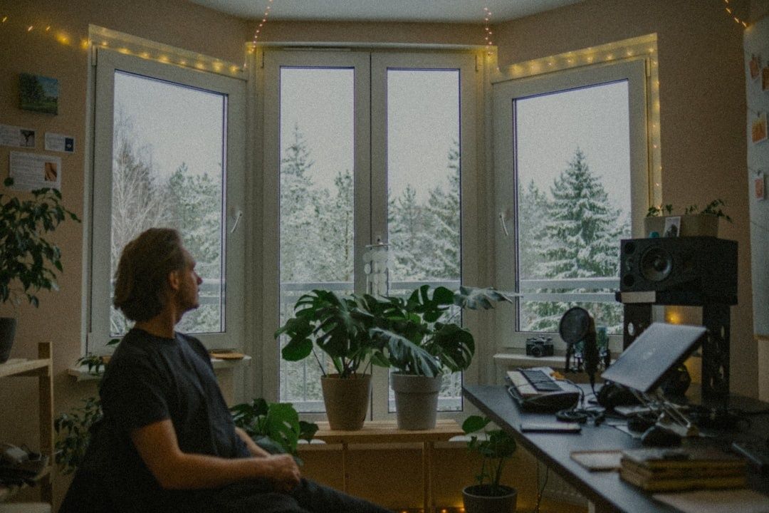Person sitter vid skrivbord med växter och skog utanför fönstret