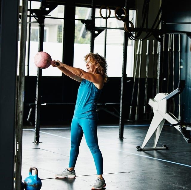 Mogen kvinna tränar med medicinboll i ett gym